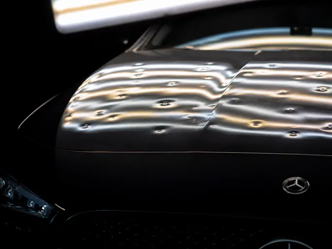Professionelle Hagelschaden Reparatur ohne Lackieren Fahrzeug mit sichtbarem Hagelschaden auf der Motorhaube vor der lackschadenfreien Reparatur
