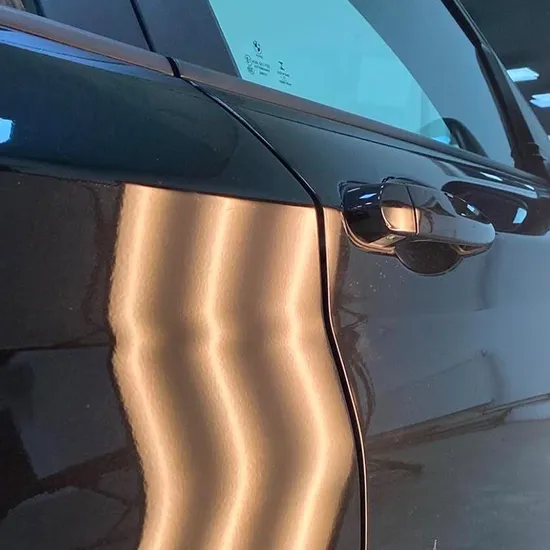 Parkdelle an einer schwarzen Fahrzeugtür nach der Reparatur
